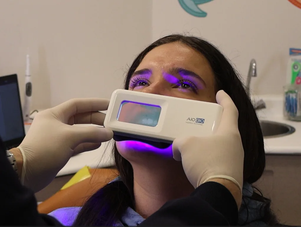 Clínico usando QScan Plus com luz QLF sobre paciente