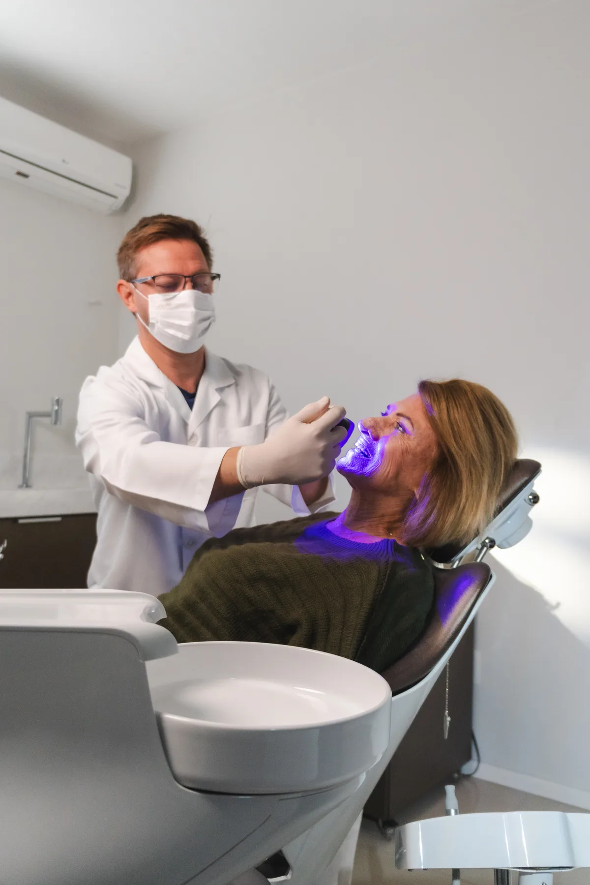 Dentista aplicando QScan Plus em paciente idosa durante consulta